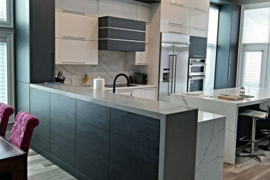 Photo of a large contemporary l-shaped eat-in kitchen in Toronto with an undermount sink, flat-panel cabinets, white cabinets, quartz benchtops, white splashback, stone slab splashback, stainless steel appliances, vinyl floors, multiple islands, grey floor and white benchtop.