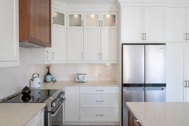 Example of a mid-sized trendy l-shaped kitchen design in Toronto with a single-bowl sink, recessed-panel cabinets, white cabinets, white backsplash, subway tile backsplash, stainless steel appliances, an island and beige countertops