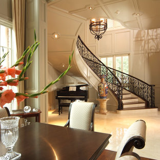 Ejemplo de escalera curva, tradicional, grande, con escalones de madera, contrahuellas de mármol y barandilla de metal