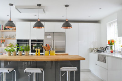 Inspiration for a medium sized contemporary kitchen in Berkshire with flat-panel cabinets, white cabinets and an island.