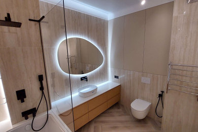 На фото: ванная комната среднего размера в стиле модернизм с бежевыми фасадами, ванной на ножках, душем над ванной, инсталляцией, бежевой плиткой, керамогранитной плиткой, бежевыми стенами, полом из керамогранита, настольной раковиной, бежевым полом, белой столешницей, зеркалом с подсветкой и тумбой под одну раковину