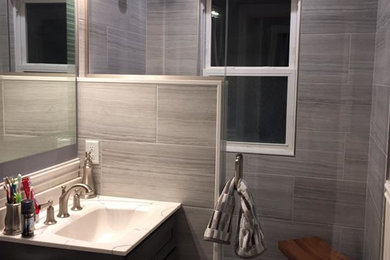 Example of a mid-sized trendy gray tile and ceramic tile ceramic tile and gray floor doorless shower design in Boston with shaker cabinets, dark wood cabinets, a one-piece toilet, gray walls and a drop-in sink