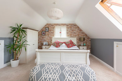 This is an example of a mid-sized country guest bedroom in Dorset with grey walls, carpet, beige floor and no fireplace.