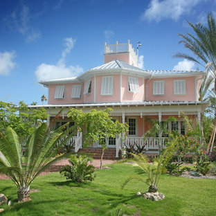 マイアミのトロピカルスタイルのおしゃれな二階建ての家 (ピンクの外壁) の写真
