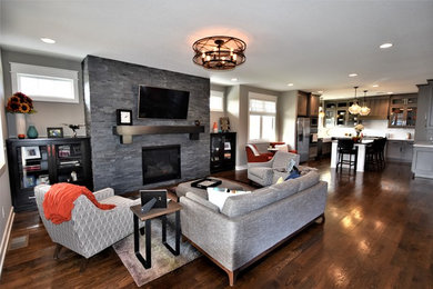 Inspiration for a mid-sized craftsman open concept dark wood floor living room remodel in Kansas City with gray walls, a standard fireplace, a stone fireplace and a wall-mounted tv