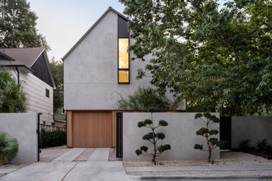Small modern gray two-story stucco house exterior idea in Austin with a clipped gable roof, a metal roof and a black roof