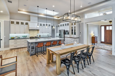 Inspiration for a large transitional l-shaped light wood floor and beige floor open concept kitchen remodel in San Francisco with an undermount sink, shaker cabinets, white cabinets, stainless steel appliances, an island, white countertops, granite countertops, white backsplash and glass tile backsplash