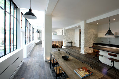 Cette photo montre une grande salle à manger ouverte sur le salon industrielle avec un mur blanc, parquet foncé, aucune cheminée et un sol marron.