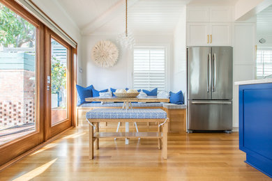 Small beach style galley medium tone wood floor eat-in kitchen photo in Miami with white cabinets, marble countertops, stainless steel appliances and no island