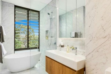 Design ideas for a large contemporary master bathroom in Wollongong with a one-piece toilet, marble floors, an integrated sink and an open shower.