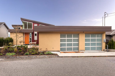 Contemporary yellow three-story stucco exterior home idea in Vancouver