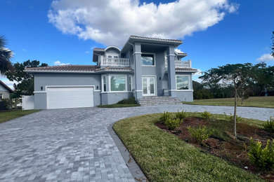 Inspiration for a large mediterranean gray two-story stucco house exterior remodel in Tampa with a hip roof, a tile roof and a brown roof