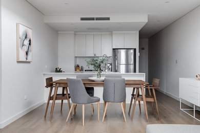 Inspiration for a mid-sized scandinavian open plan dining in Sydney with white walls, light hardwood floors, no fireplace and brown floor.