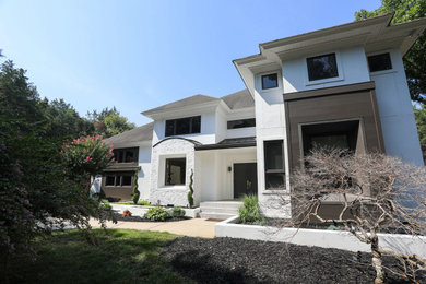 Example of a large minimalist white two-story house exterior design in Charlotte with a brown roof