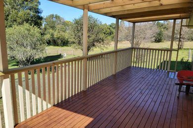 Inspiration for a mid-sized country balcony in Other with a roof extension and wood railing.