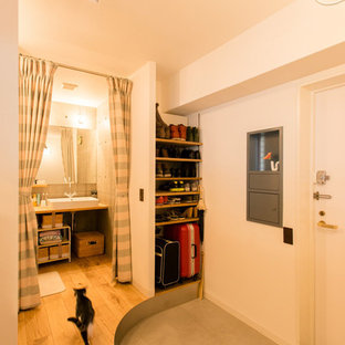 横浜の中サイズの片開きドア北欧スタイルのおしゃれな玄関ホール (白い壁、コンクリートの床、白いドア、グレーの床) の写真