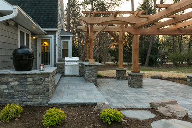 Photo of a large country backyard patio in Charlotte with an outdoor kitchen, concrete pavers and a pergola.