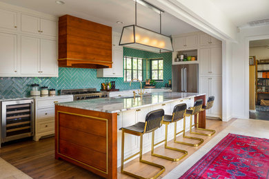 Photo of a large transitional u-shaped open plan kitchen in Austin with an undermount sink, quartzite benchtops, green splashback, ceramic splashback, stainless steel appliances, medium hardwood floors, with island, brown floor, multi-coloured benchtop, beaded inset cabinets and white cabinets.