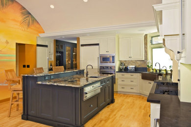 Inspiration for a large timeless l-shaped light wood floor kitchen remodel in San Francisco with a farmhouse sink, beaded inset cabinets, white cabinets, granite countertops, stainless steel appliances and an island