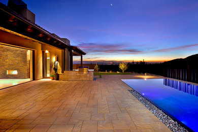 Pool - large contemporary backyard stone and rectangular infinity pool idea in Phoenix