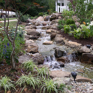 Photo of a small tropical sloped shaded garden for summer in Kansas City with mulch and with waterfall.