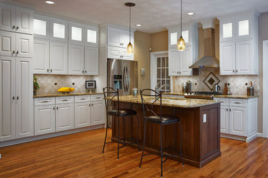 Elegant l-shaped medium tone wood floor eat-in kitchen photo in Providence with an undermount sink, raised-panel cabinets, white cabinets, granite countertops, beige backsplash, stone tile backsplash, stainless steel appliances and an island
