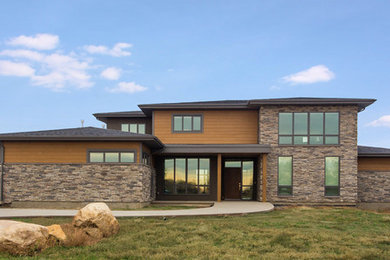 Large two-storey grey exterior in Calgary with stone veneer and a hip roof.