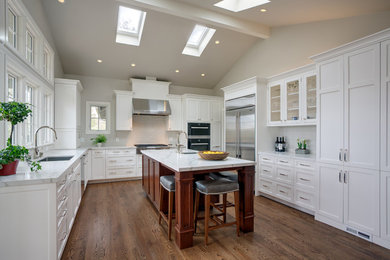 Large elegant u-shaped medium tone wood floor and brown floor open concept kitchen photo in San Francisco with an undermount sink, recessed-panel cabinets, white cabinets, quartz countertops, white backsplash, stainless steel appliances and an island