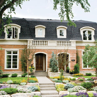 カルガリーのトラディショナルスタイルのおしゃれな二階建ての家 (レンガサイディング、赤い外壁、デュープレックス、板屋根) の写真