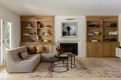 Diseño de sala de estar con biblioteca abierta campestre de tamaño medio con suelo de travertino, todas las chimeneas y marco de chimenea de yeso