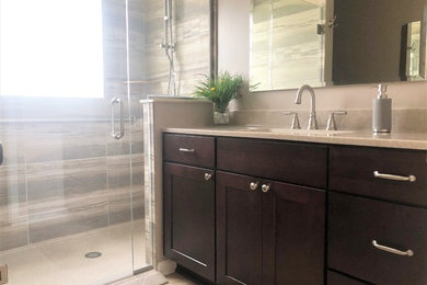 Corner shower - mid-sized contemporary 3/4 laminate floor corner shower idea in Detroit with recessed-panel cabinets, dark wood cabinets, a one-piece toilet, beige walls, an integrated sink, a hinged shower door and beige countertops