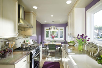 Inspiration for a large modern galley marble floor eat-in kitchen remodel in Sacramento with a farmhouse sink, raised-panel cabinets, white cabinets, granite countertops, green backsplash, glass tile backsplash, black appliances and a peninsula
