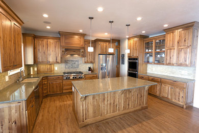 Inspiration for a large country u-shaped eat-in kitchen in Salt Lake City with an undermount sink, raised-panel cabinets, medium wood cabinets, granite benchtops, beige splashback, ceramic splashback, stainless steel appliances, vinyl floors and with island.