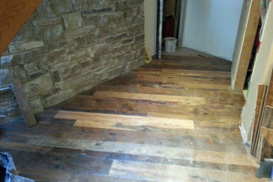 Mid-sized mountain style walk-out dark wood floor and brown floor basement photo in Other with a wood stove and a stone fireplace
