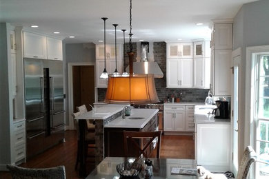 Eat-in kitchen - large contemporary l-shaped brown floor eat-in kitchen idea in New York with a single-bowl sink, flat-panel cabinets, white cabinets, quartz countertops, multicolored backsplash, mosaic tile backsplash, stainless steel appliances and an island