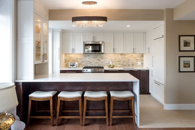 Inspiration for a mid-sized transitional u-shaped slate floor kitchen remodel in New York with an undermount sink, shaker cabinets, white cabinets, quartz countertops, beige backsplash, stone tile backsplash, stainless steel appliances and an island