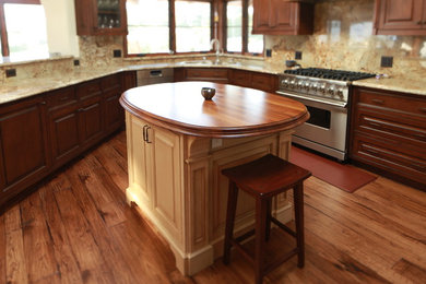 Open concept kitchen - large traditional u-shaped medium tone wood floor open concept kitchen idea in Los Angeles with an undermount sink, raised-panel cabinets, medium tone wood cabinets, granite countertops, beige backsplash, stone slab backsplash, stainless steel appliances and an island