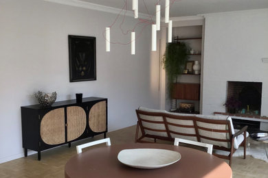 Immagine di una sala da pranzo aperta verso il soggiorno di medie dimensioni con parquet chiaro e camino classico