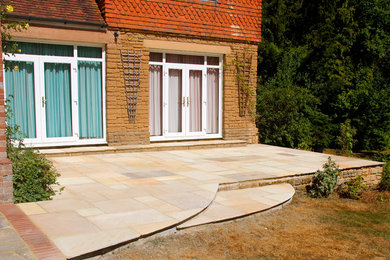 Photo of a traditional back patio in Sussex with natural stone paving.