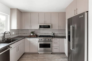 Example of a small minimalist u-shaped porcelain tile and multicolored floor eat-in kitchen design in San Luis Obispo with an undermount sink, flat-panel cabinets, beige cabinets, granite countertops, multicolored backsplash, porcelain backsplash, stainless steel appliances, no island and black countertops