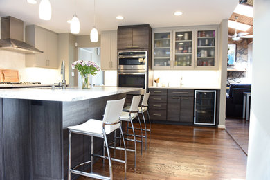 Example of a mid-sized minimalist l-shaped medium tone wood floor and brown floor eat-in kitchen design in Atlanta with an undermount sink, flat-panel cabinets, dark wood cabinets, granite countertops, white backsplash, marble backsplash, stainless steel appliances and an island