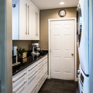 Idées déco pour une arrière-cuisine linéaire contemporaine de taille moyenne avec un placard à porte plane, des portes de placard blanches, un plan de travail en surface solide, un électroménager blanc, un sol en ardoise, aucun îlot et un sol noir.