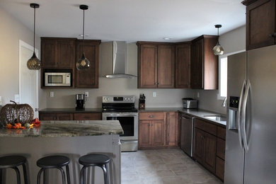 Mid-sized arts and crafts l-shaped porcelain tile eat-in kitchen photo in Philadelphia with a single-bowl sink, shaker cabinets, medium tone wood cabinets, granite countertops, stainless steel appliances and an island