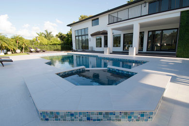 Inspiration for a mid-sized contemporary backyard custom-shaped pool in Miami with tile.