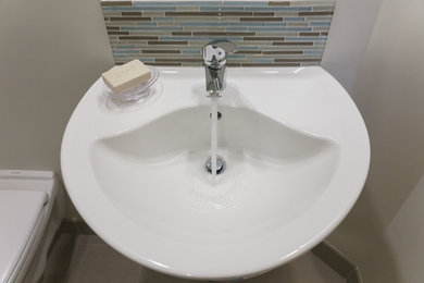 Inspiration for a small beach style 3/4 bathroom in Vancouver with a wall-mount sink, flat-panel cabinets, white cabinets, a double shower, a wall-mount toilet, multi-coloured tile, glass tile, beige walls and ceramic floors.