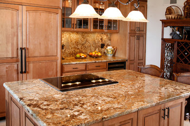 Inspiration for a timeless u-shaped eat-in kitchen remodel in San Diego with an undermount sink, raised-panel cabinets, medium tone wood cabinets, granite countertops, stone slab backsplash and paneled appliances