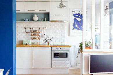 Ejemplo de cocina lineal minimalista de tamaño medio abierta sin isla con salpicadero blanco, salpicadero de azulejos de cerámica, electrodomésticos blancos y suelo de madera clara
