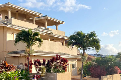 This is an example of an expansive and beige contemporary render detached house in Hawaii with three floors and a tiled roof.
