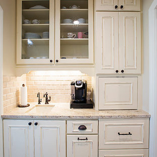 Cette photo montre une arrière-cuisine parallèle chic de taille moyenne avec un évier encastré, un placard avec porte à panneau encastré, des portes de placard en bois vieilli, un plan de travail en granite, une crédence beige, une crédence en carreau de ciment, un électroménager en acier inoxydable, un sol en carreaux de ciment, un sol gris et un plan de travail blanc.