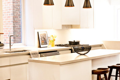 Mid-sized trendy single-wall medium tone wood floor and brown floor eat-in kitchen photo in Toronto with an undermount sink, flat-panel cabinets, white cabinets, quartzite countertops, white backsplash, stone slab backsplash, stainless steel appliances, an island and white countertops